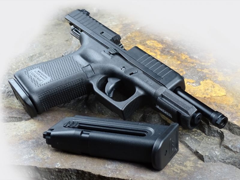 Celkový pohled na nový model Glock 44 se závěrem v zadní poloze ve verzi s prodlouženou hlavní se závitem na jejím konci. I nový Glock 44 má pravo-levé ovládání záchytu závěru.