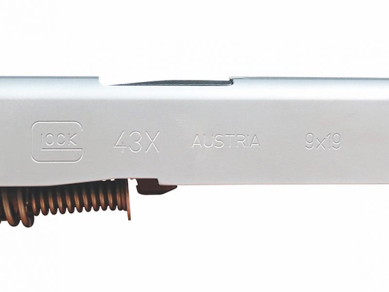 Boční pohled na kompletní ocelový závěr Glocku 43X spolu s hlavní a předsuvnou pružinou. Ocelový závěr má standardně přední úchopové hmatníky a je barevně upraven do stříbrného odstínu (nPVD).